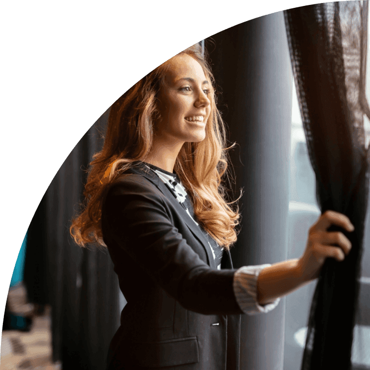 An entrepreneur smiling by a window, framed by the LLCity quarter-circle curve